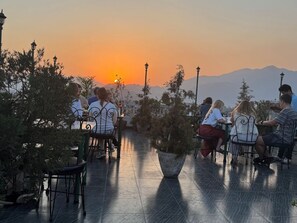 A terrace with outdoor seating, potted plants, and a sunset view. - Hotel Nepalaya (Kathmandu)