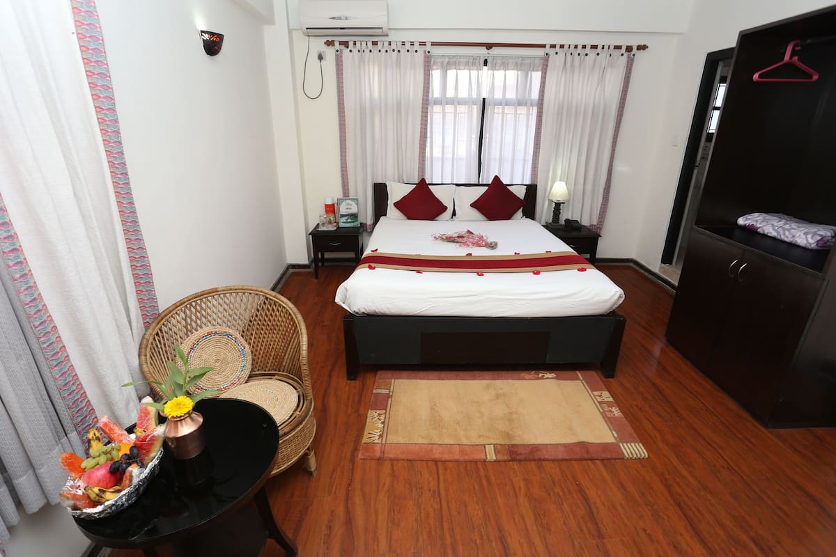 A neatly arranged hotel room with a bed, bedside tables, a chair, and a wardrobe.
