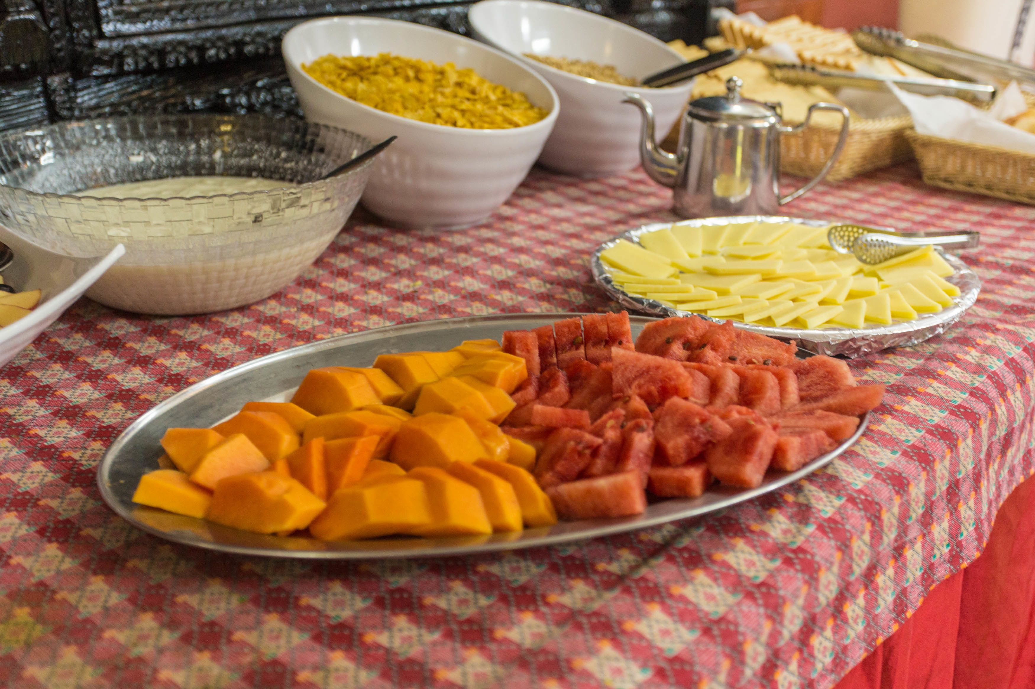 A buffet table with various dishes including fruit and cheese.