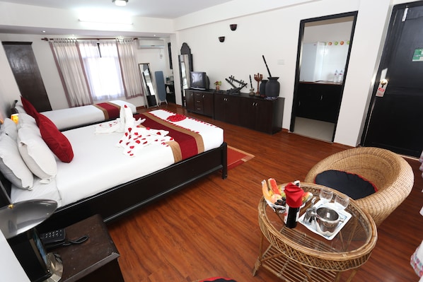 Una habitación de hotel con una cama, televisión, una mesa de comedor con una cesta y una silla de mimbre.