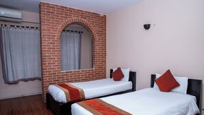 A hotel room with two single beds, a brick wall, an arched doorway, and an air conditioning unit. - Thamel Eco Resort (Kathmandu)