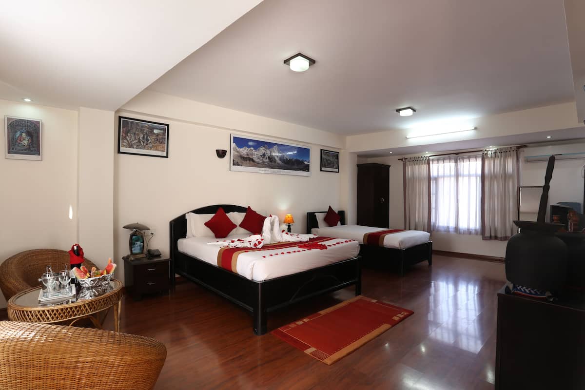 A hotel room with two beds, a dining table, a chair, and artwork on the walls.
