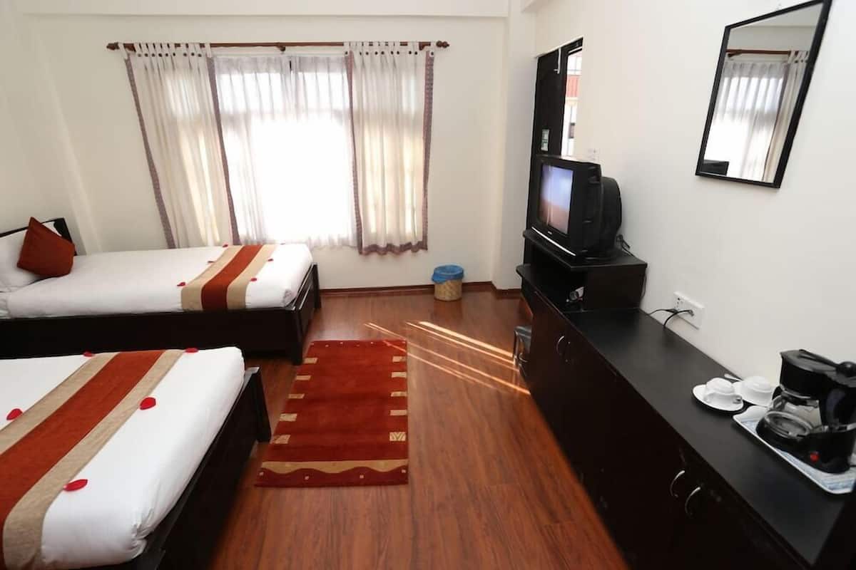 A hotel room with two beds, a television, a coffee maker, and a mirror.