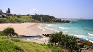 A coastal beach with a swimming pool, a lighthouse, and a rocky shoreline. - The Carmel Yamba (Yamba)