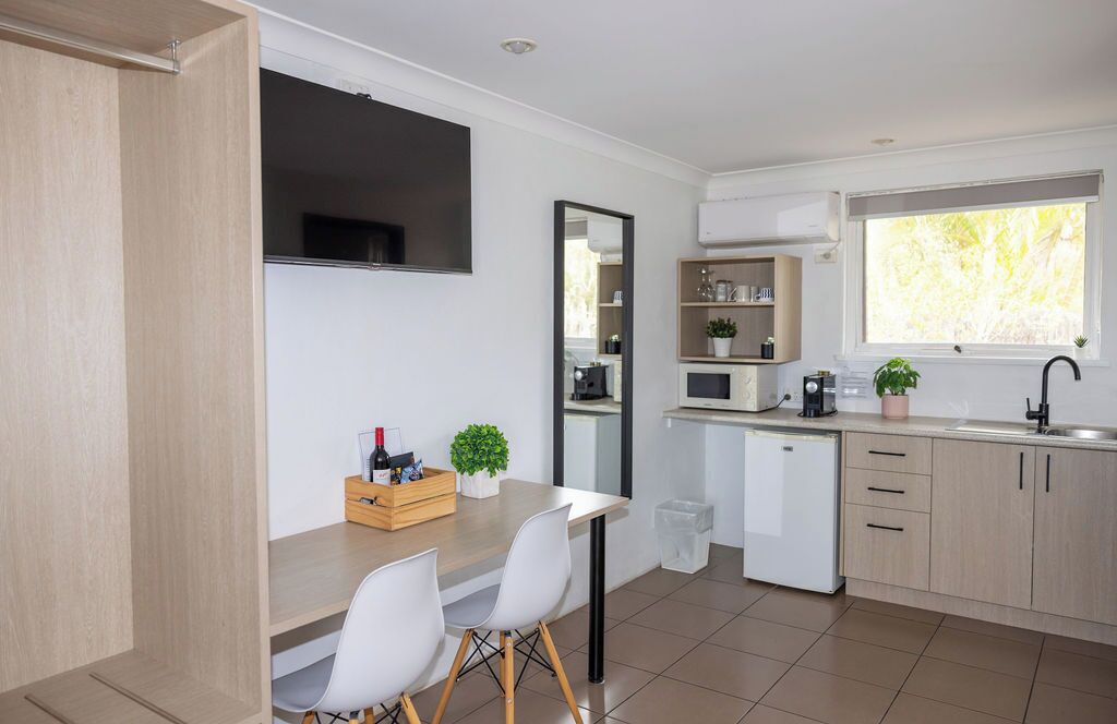 A modern kitchen with a dining area, a built-in microwave, a sink, and a window with a view.