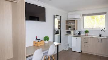 A modern kitchen with a dining area, a built-in microwave, a sink, and a window with a view.