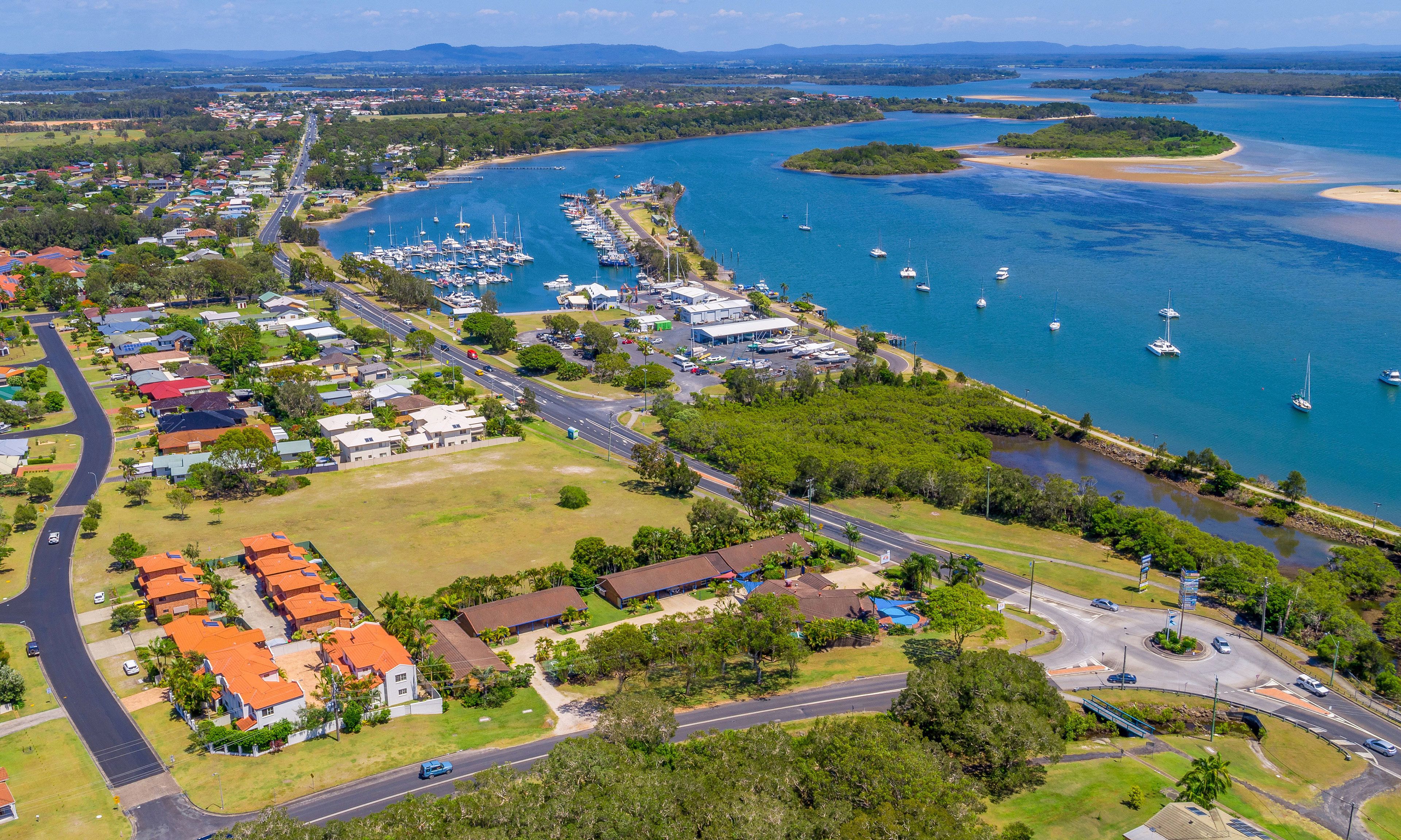 An aerial view of a coastal town with a marina, residential areas, and roads.