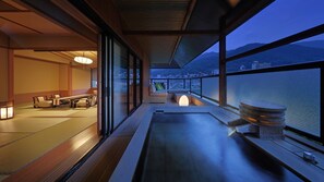 A traditional Japanese room with tatami flooring, a tatami mat table, and a low wooden table with cushions.