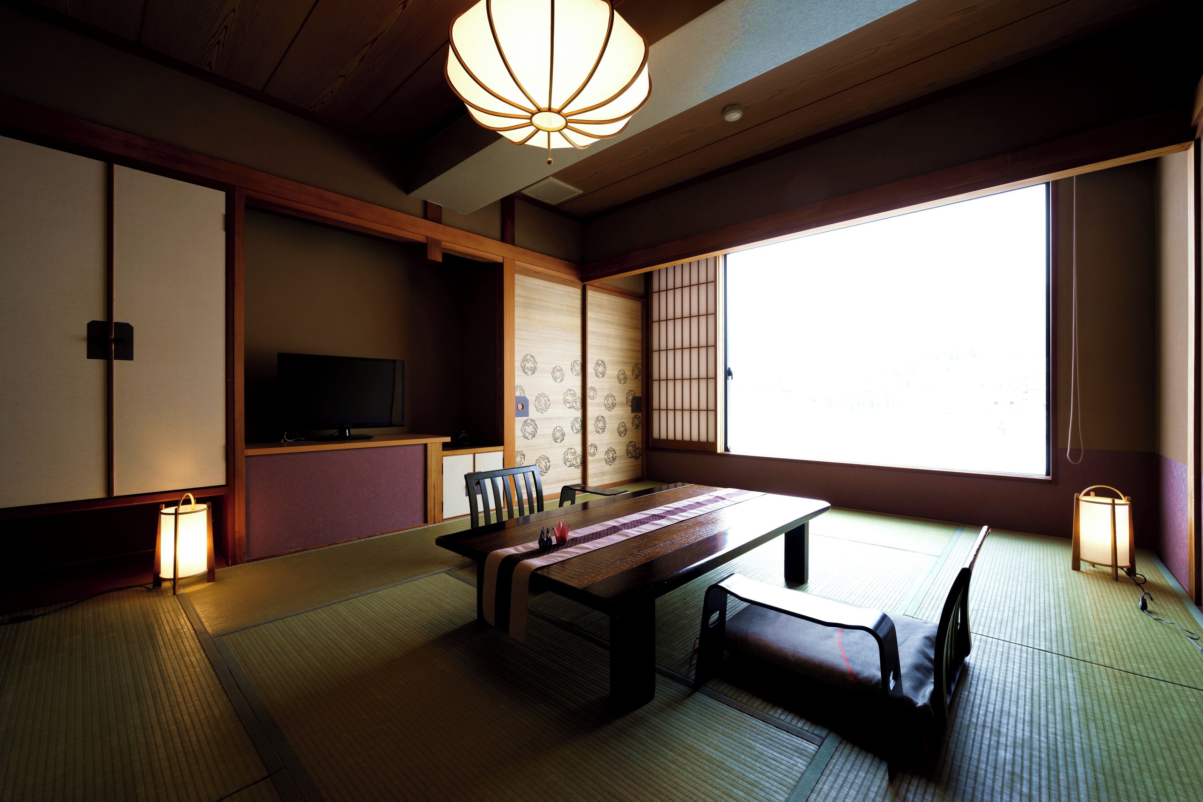 A traditional Japanese room with tatami flooring, a low table, a sofa, and sliding doors.