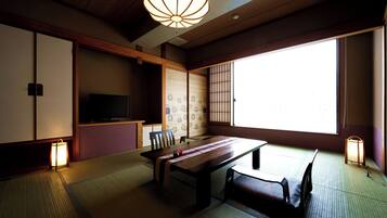 A traditional Japanese room with tatami flooring, a low table, a sofa, and sliding doors.