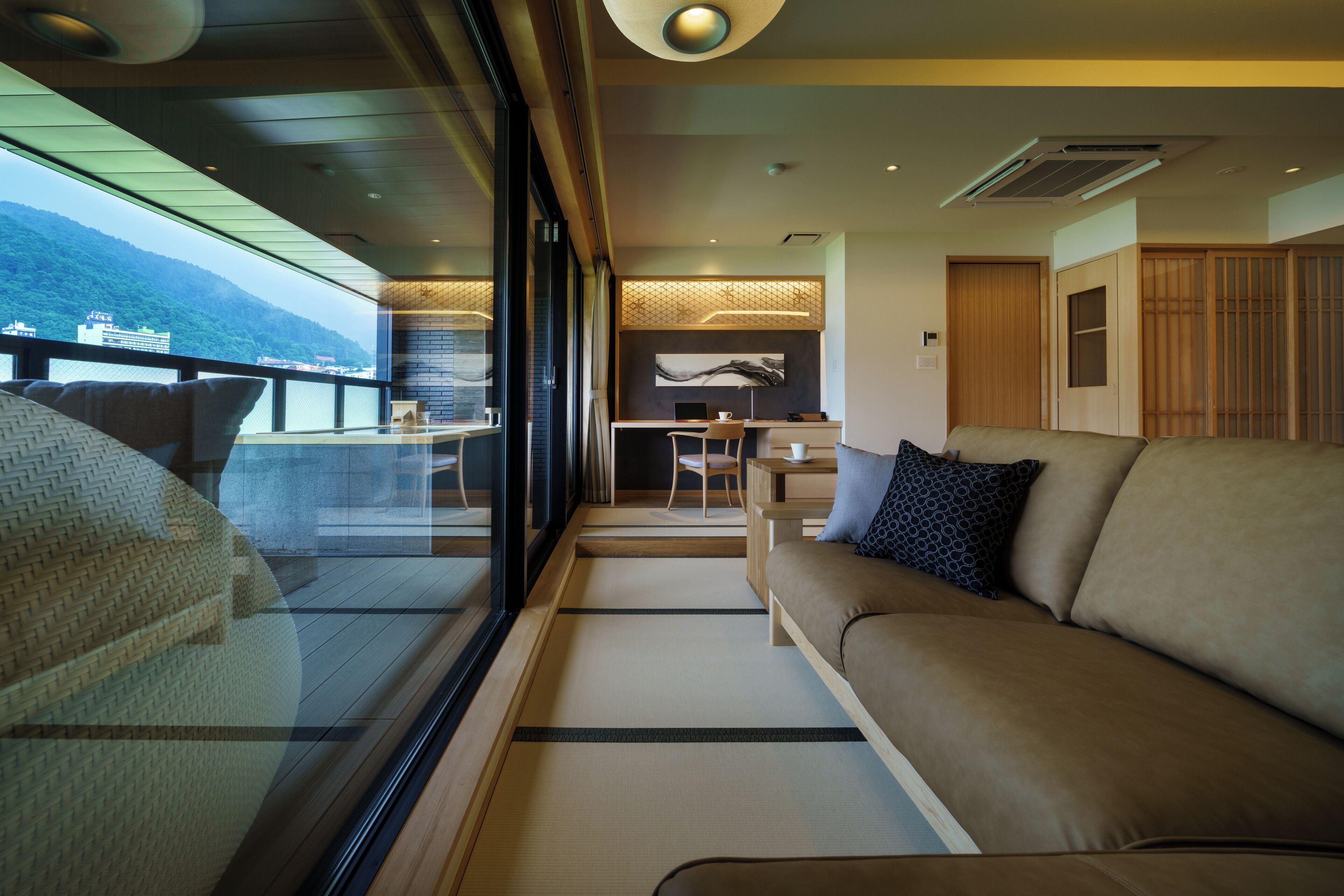 A modern interior with a sofa, a dining area, and a view of the sea.