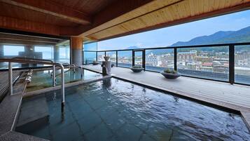 An indoor swimming pool with a view of a cityscape and mountains.