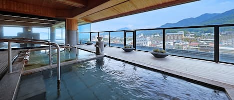 An indoor swimming pool with a view of a cityscape and mountains.