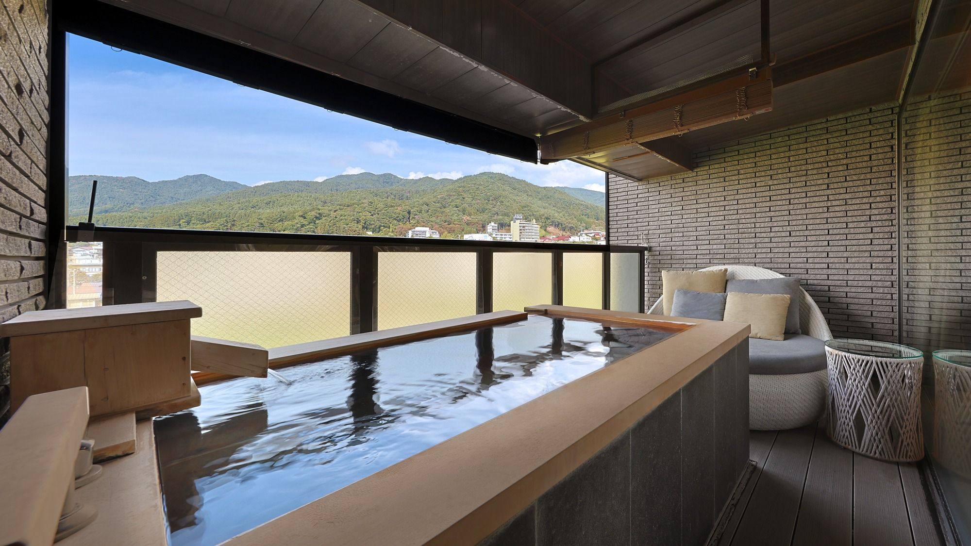 A room with a wooden bench, a small table, and a view of mountains through a large window.