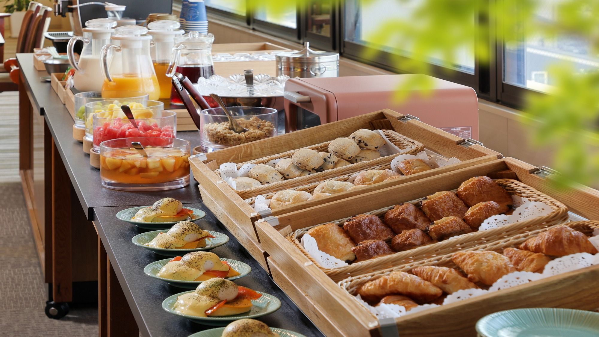 A buffet with various breakfast items including pastries, eggs benedict, and fruit.