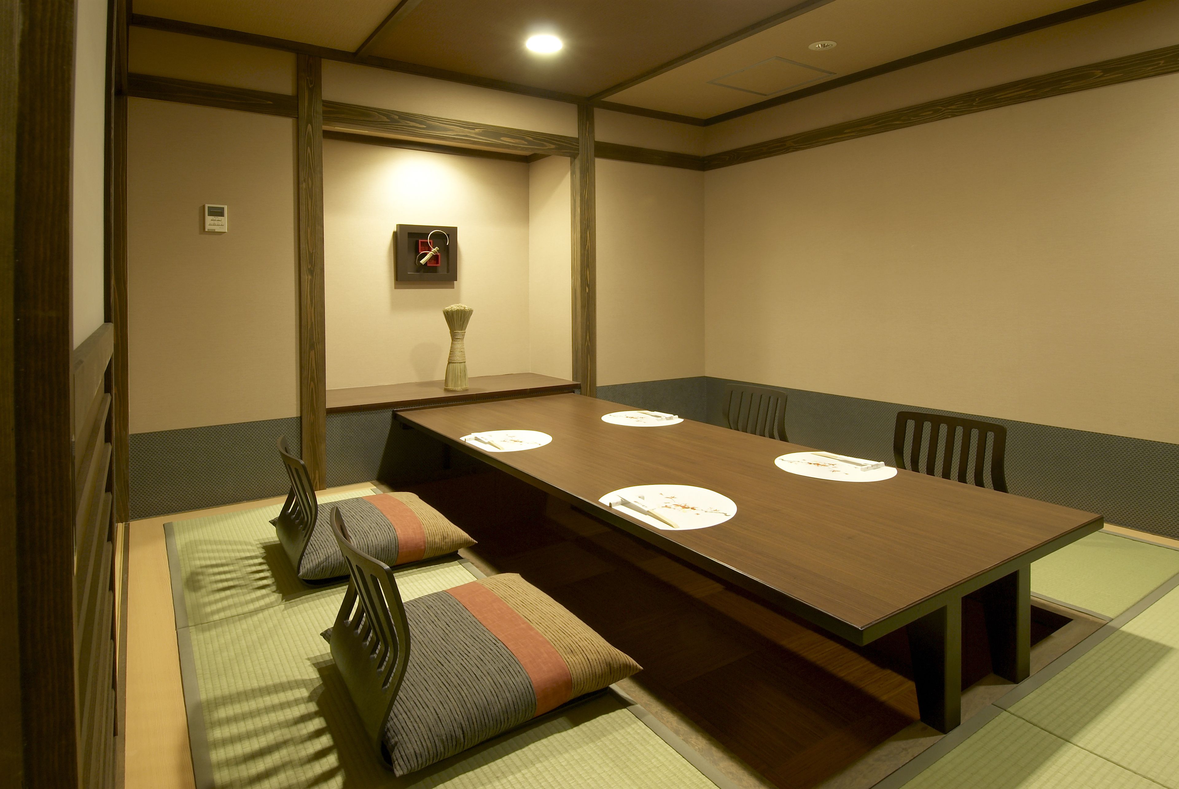 A traditional Japanese-style room with tatami mats, a low wooden table, and a simple wall-mounted clock.