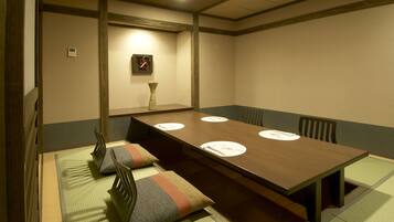 A traditional Japanese-style room with tatami mats, a low wooden table, and a simple wall-mounted clock.