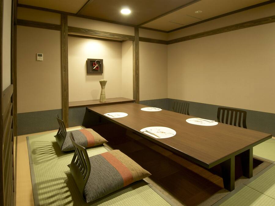 A traditional Japanese-style room with tatami mats, a low wooden table, and a simple wall-mounted clock.