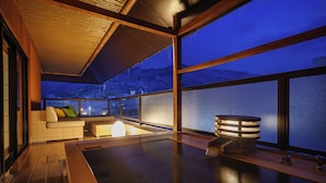 Un interior moderno con suelo de madera, un sofá con cojines, una mesita y un amplio ventanal con vistas a montañas nevadas.