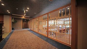 A hallway with a patterned carpet, wooden sliding doors with lattice designs, and recessed ceiling lights.