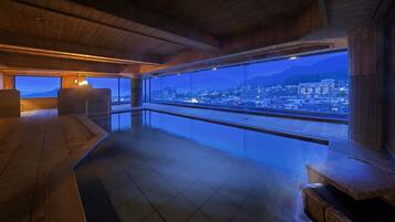 A modern interior with a large panoramic window overlooking a cityscape at dusk.