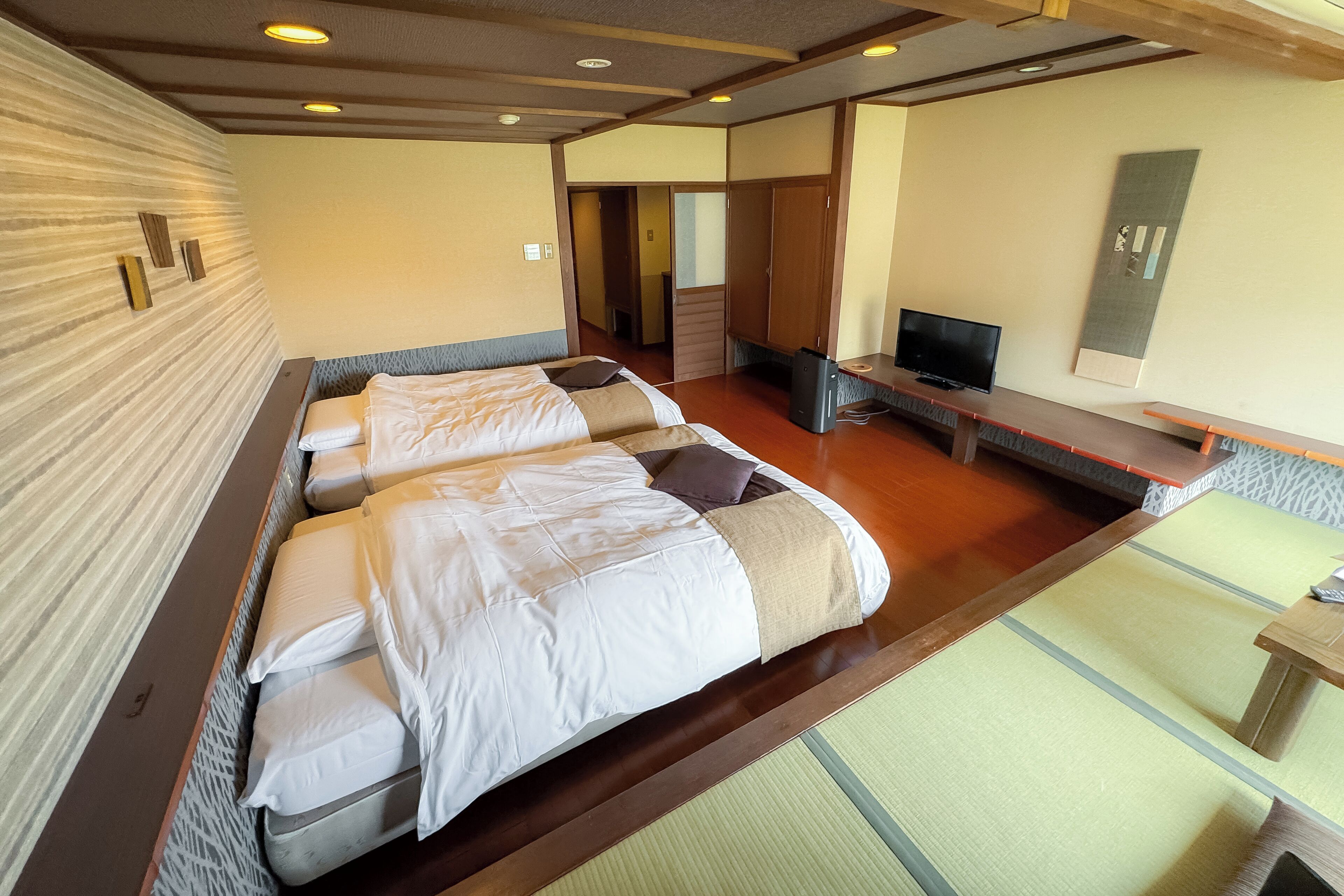 A hotel room with a large bed, a TV, and a wooden desk.