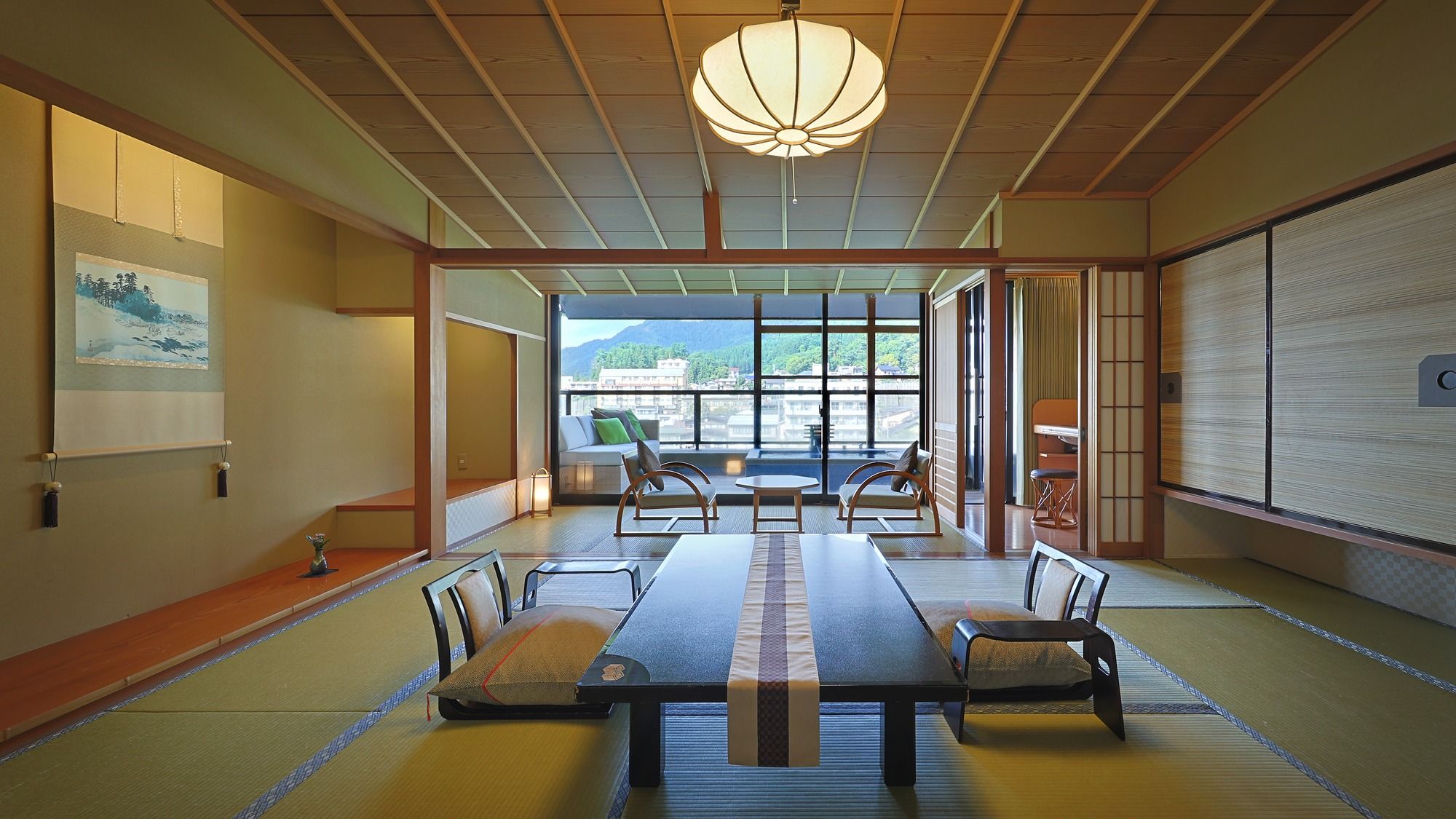 A traditional Japanese room with tatami flooring, a low table with cushions, and a view of a cityscape through large windows.