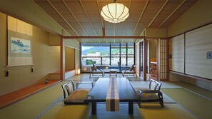 A traditional Japanese room with tatami flooring, a low table with cushions, and a view of a cityscape through large windows. - Aburaya Tosen (Yamanouchi)