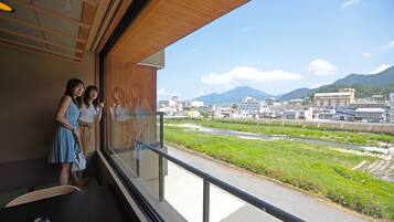A room with a large window overlooking a river and mountains.