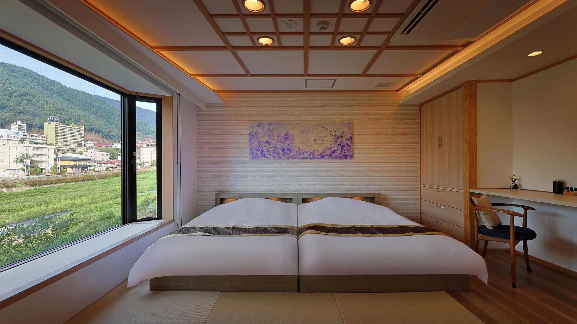 A bedroom with a large bed, a view of a green landscape, and a wooden ceiling.