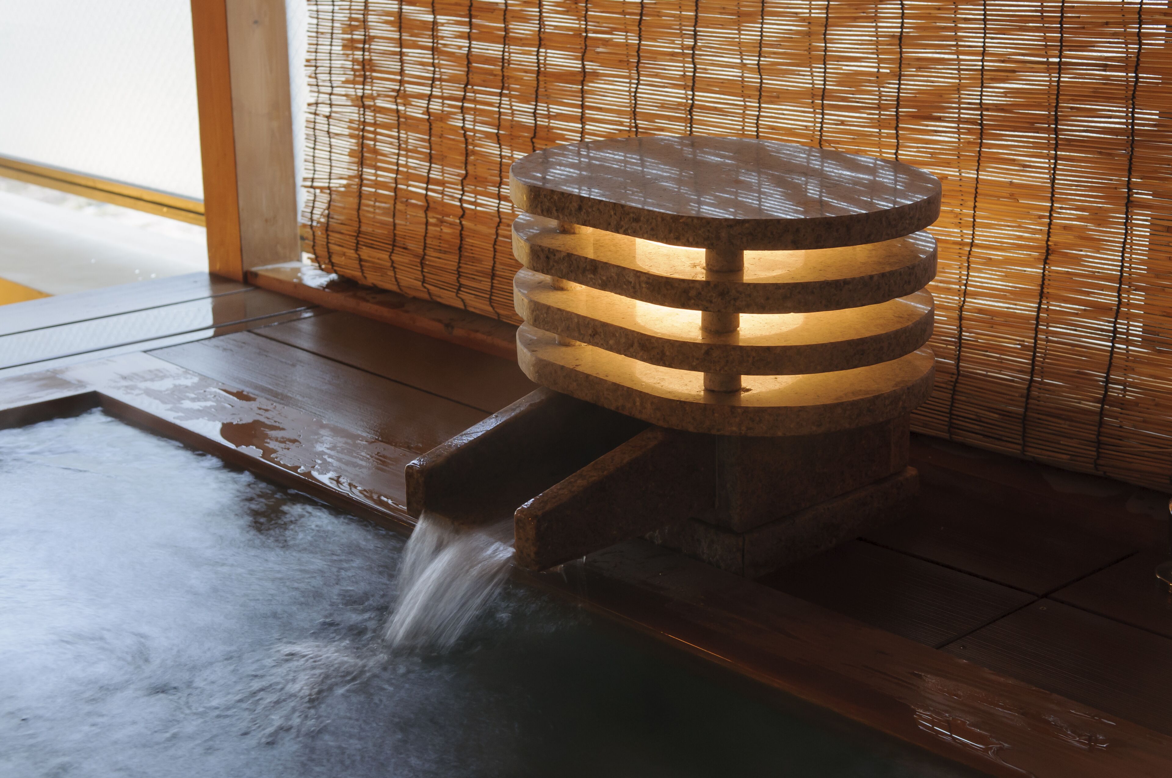 Una fuente japonesa tradicional con un cuenco de piedra y una estructura de madera que emite agua.
