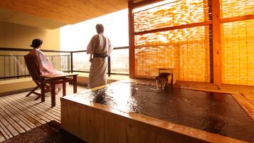 A traditional Japanese onsen with a wooden interior, a hot spring bath, and a view through a large window.