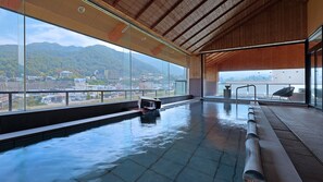 A modern indoor swimming pool with a view of a cityscape and mountains. - Aburaya Tosen (Yamanouchi)