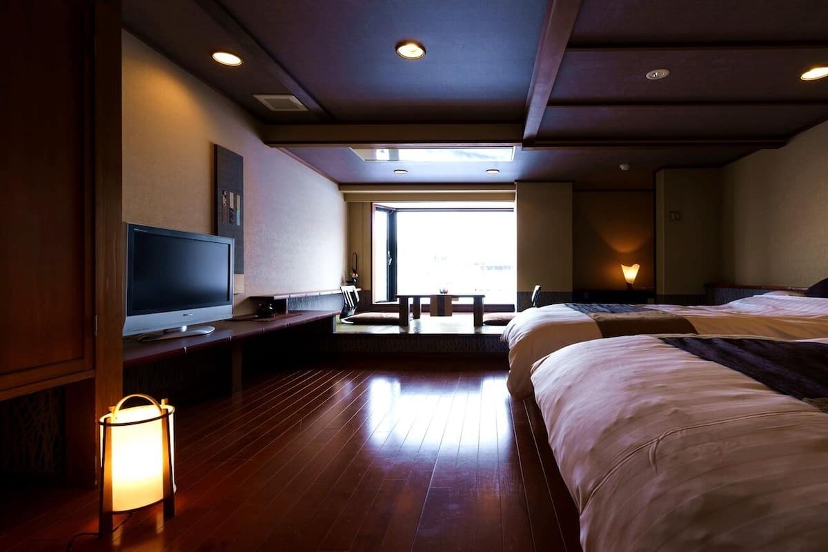 Une chambre d’hôtel avec deux lits, une télévision, un bureau, une lampe et une vue sur l’extérieur.