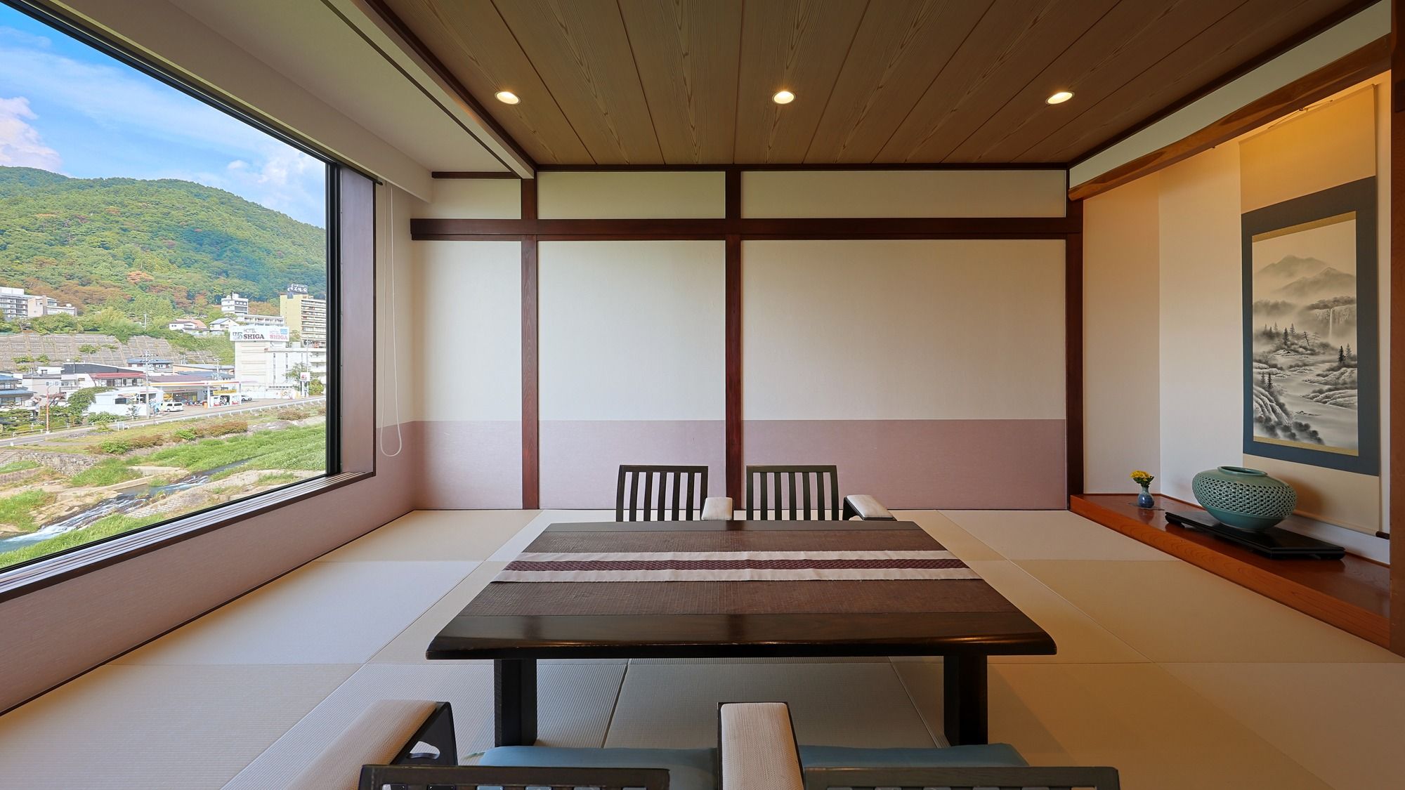 A room with tatami flooring, a low table, and chairs.