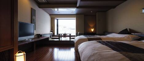 A hotel room with a large bed, a television, a desk with a lamp, and a view of the outdoors.