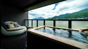 Un moderno espacio de spa con hidromasaje, un área de descanso acolchada y vistas a las montañas y al agua.