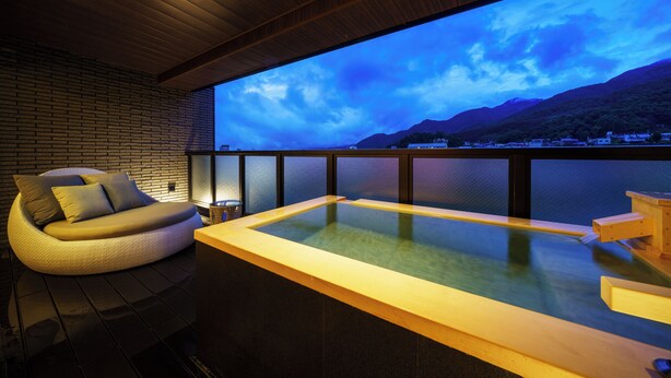 Un moderno espacio de spa con jacuzzi, una zona de estar acolchada y vistas a un paisaje montañoso.