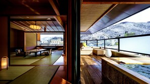 Una habitación japonesa tradicional con suelo de tatami, una mesa de madera baja y vistas a una montaña nevada.