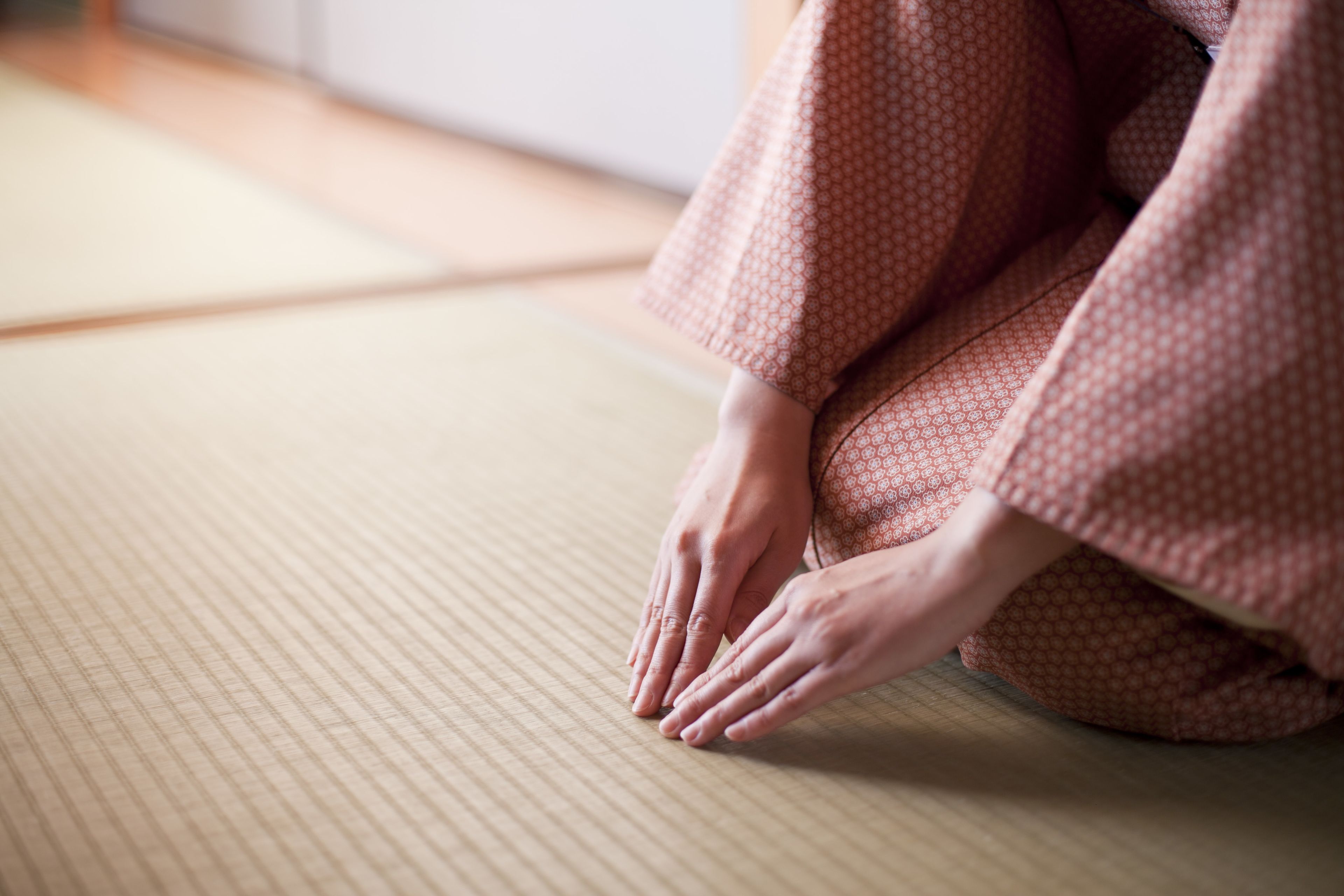 Une personne assise sur un tatami, vêtue d’un kimono à motifs.