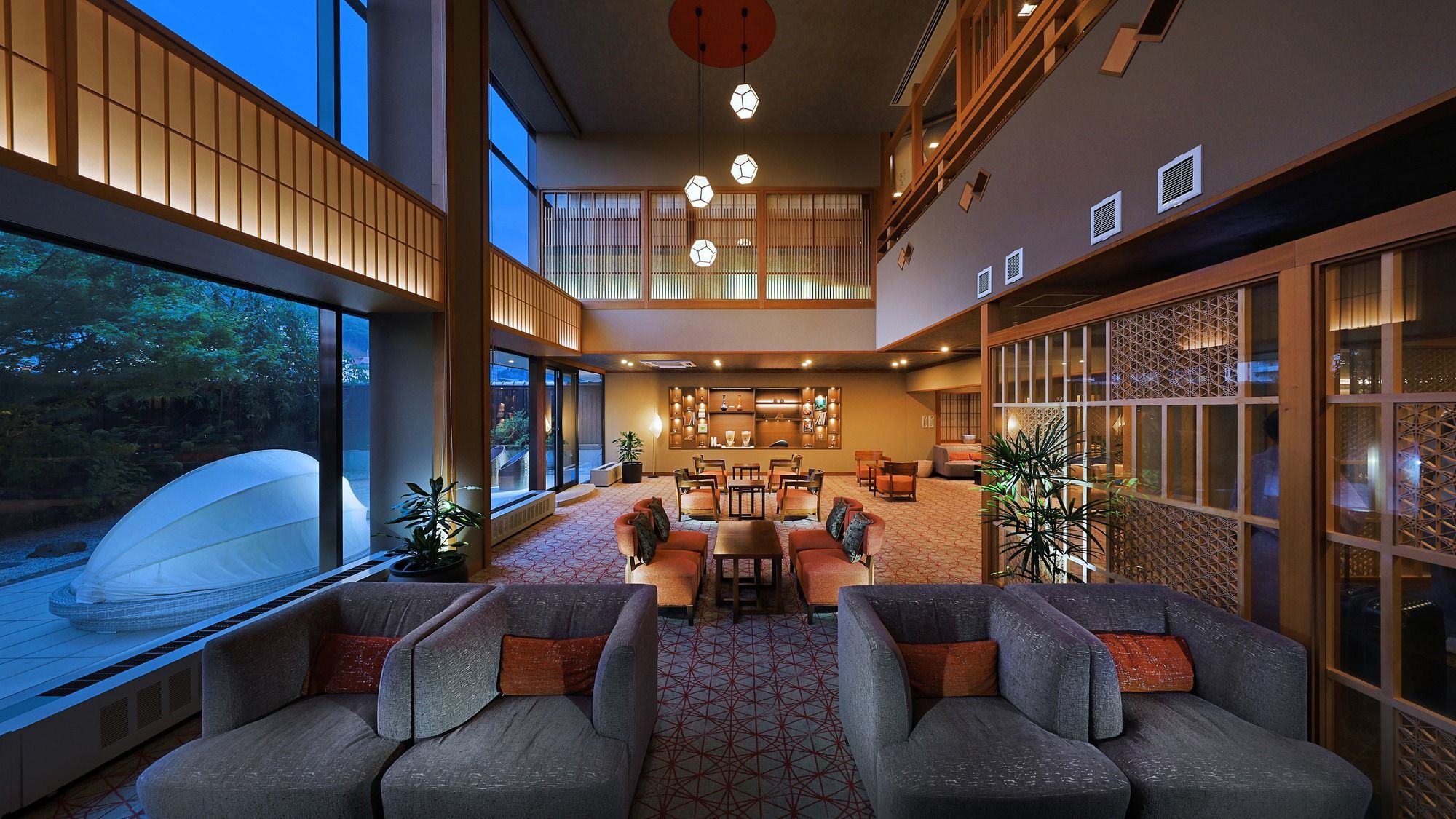 A spacious lobby with a seating area, large windows, and a view of a garden.