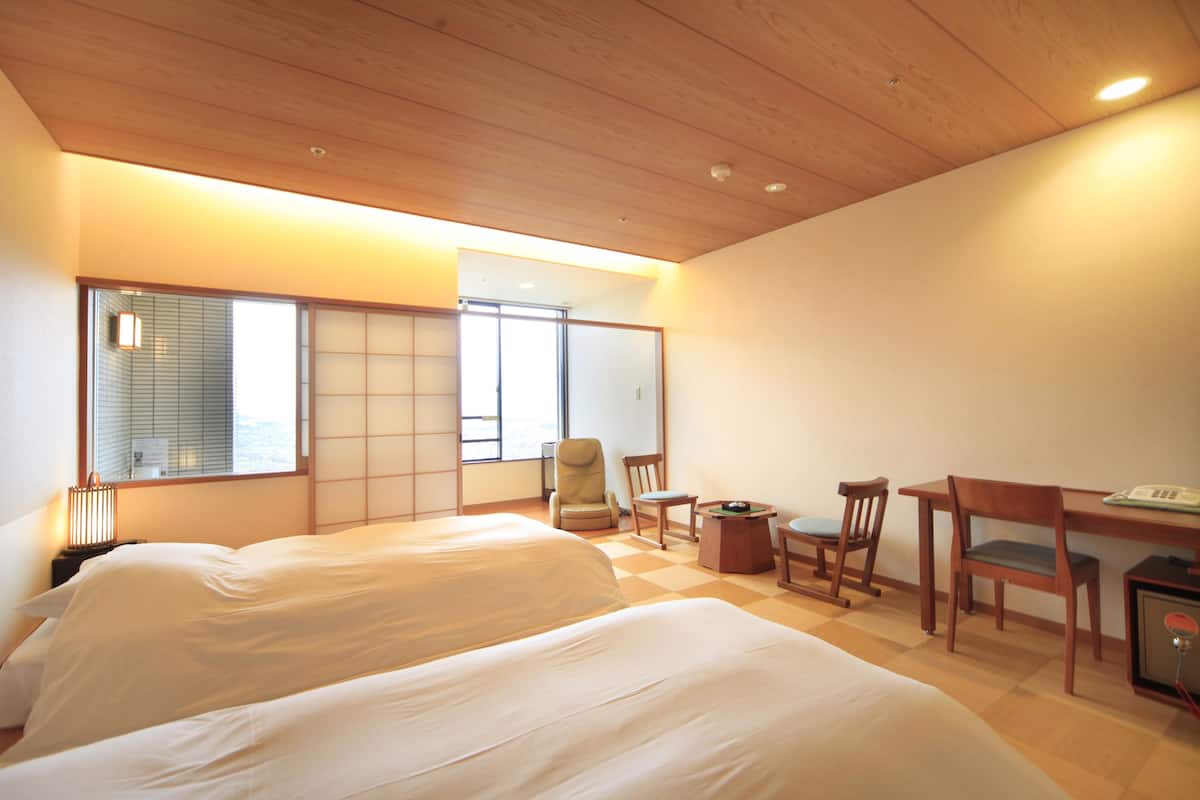 A hotel room with two beds, a desk, and chairs.