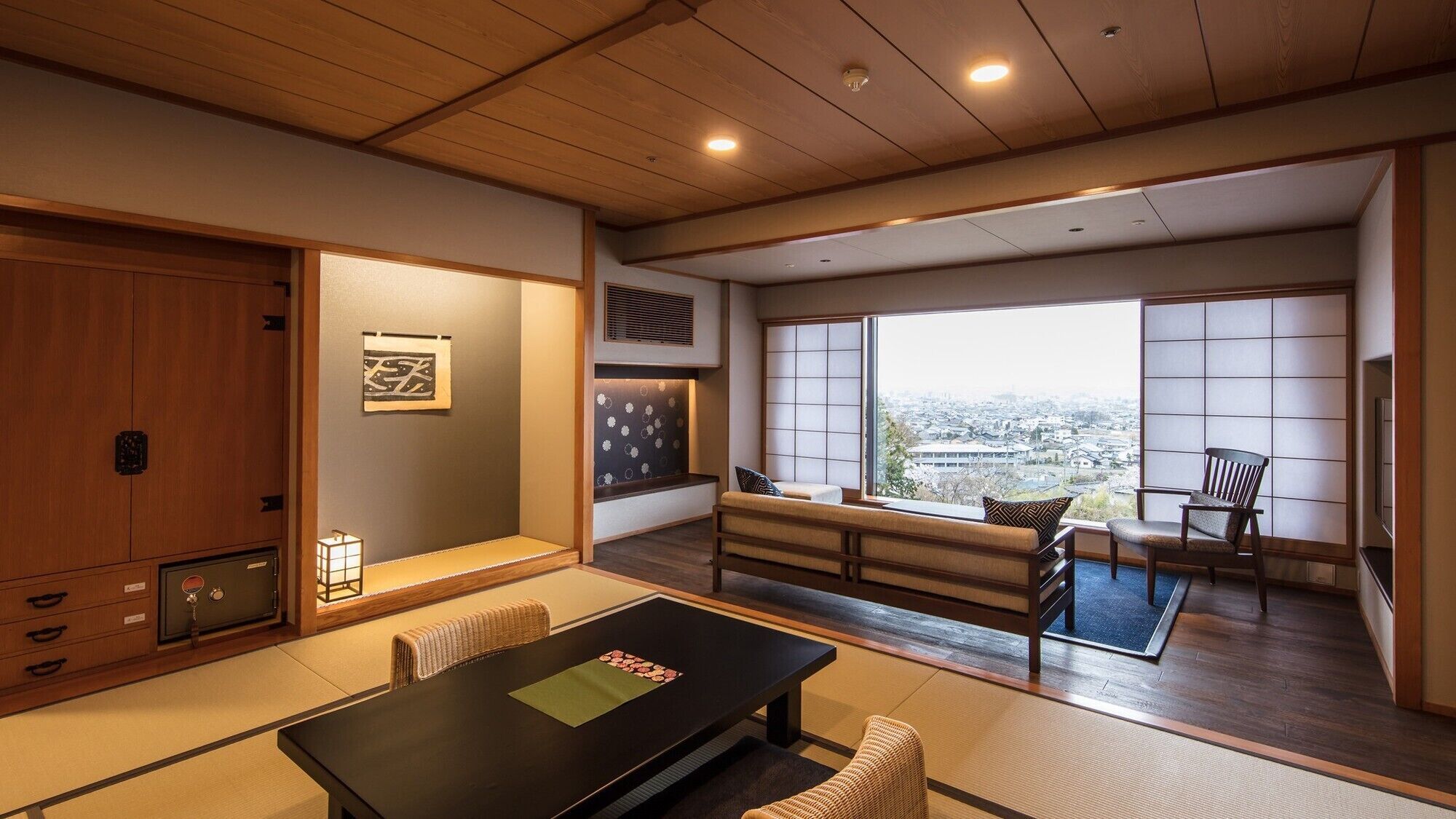 A traditional Japanese room with tatami flooring, a low table, and a view of the city.