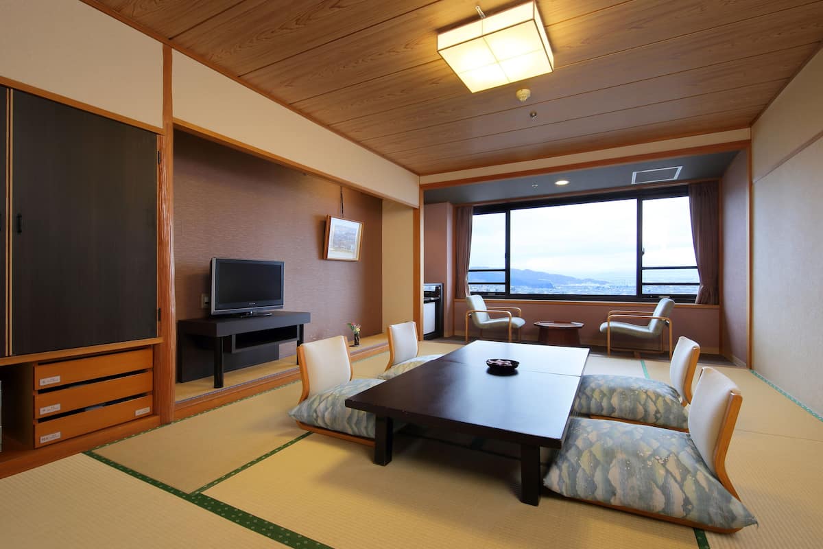 A traditional Japanese room with tatami flooring, a low table, and a television.