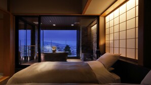 Un dormitorio con una cama grande, vistas de la ciudad y una puerta corrediza que da a un espacio al aire libre.