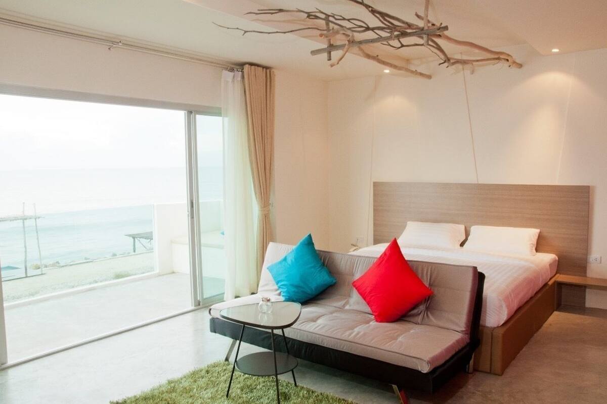 Ein modernes Schlafzimmer mit Bett, einem kleinen Tisch und Meerblick.