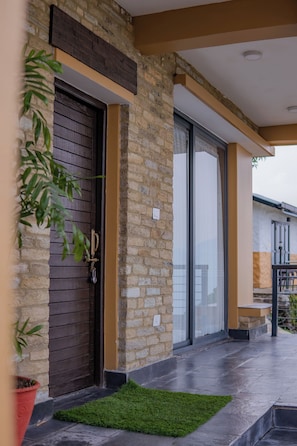 A modern building with a stone facade, a dark wooden door, and a glass entrance.