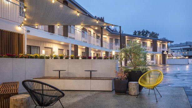 Un hotel con terraza exterior, un porche cubierto y un balcón con luces de cadena.