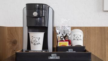 Una cafetera, una taza y un paquete de cápsulas de café sobre una bandeja negra con la leyenda 'Hotel Lumberjack'.