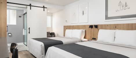 Habitación de hotel con dos camas, un escritorio, una silla y una puerta corredera.